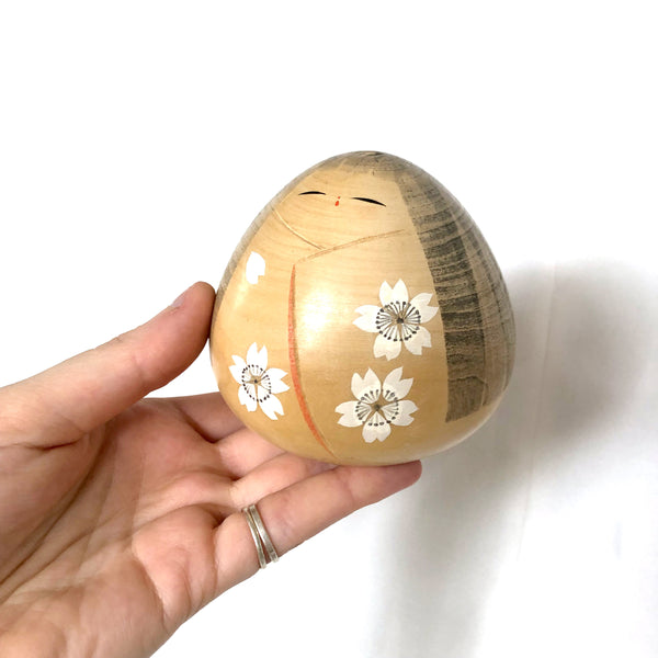 Elegant wooden kokeshi doll with sakura flowers pattern